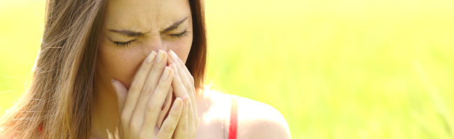 44652575 - woman with allergy coughing in a green color field in summer
